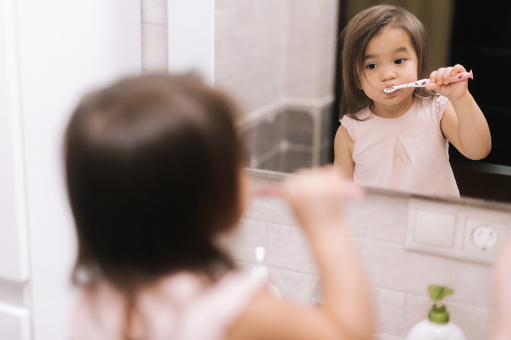 Anak perempuan sedang menggosok giginya di kamar mandi